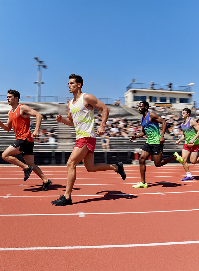 Athletes running on a track with a clear blue sky and stadium in the background